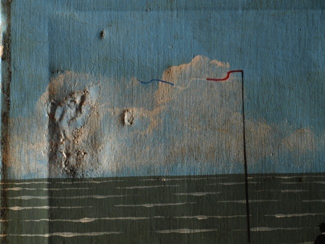 Raking light detail of surface distortion to an early 20th century beach scene caused by poor patching, before treatment